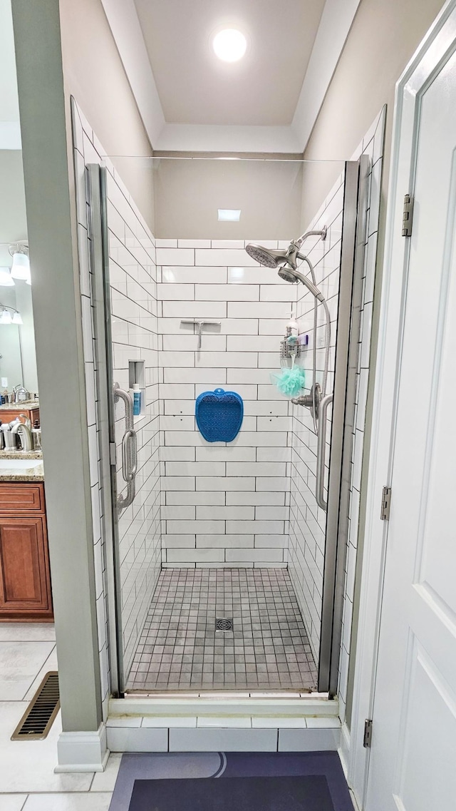 bathroom with tile patterned flooring, vanity, and walk in shower