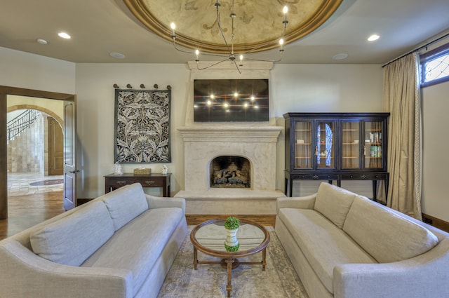 living room featuring a premium fireplace, hardwood / wood-style floors, and a tray ceiling