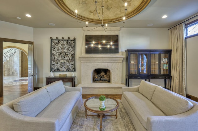 living room with recessed lighting, a tray ceiling, arched walkways, and a high end fireplace