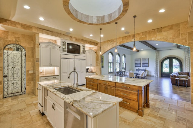 kitchen featuring arched walkways, a spacious island, a sink, and stone tile flooring