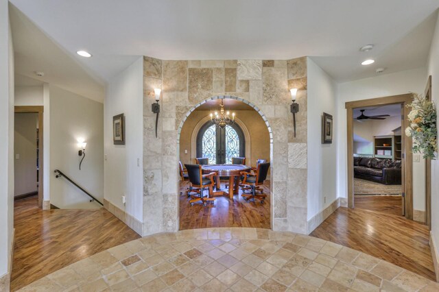 entryway featuring ceiling fan with notable chandelier, hardwood / wood-style flooring, and tile walls