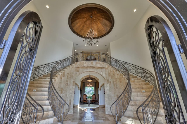 foyer entrance with arched walkways, a high ceiling, stairway, and a notable chandelier