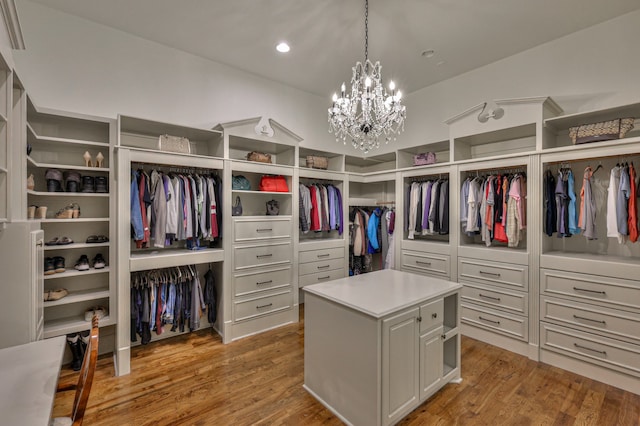 spacious closet with an inviting chandelier and light hardwood / wood-style flooring