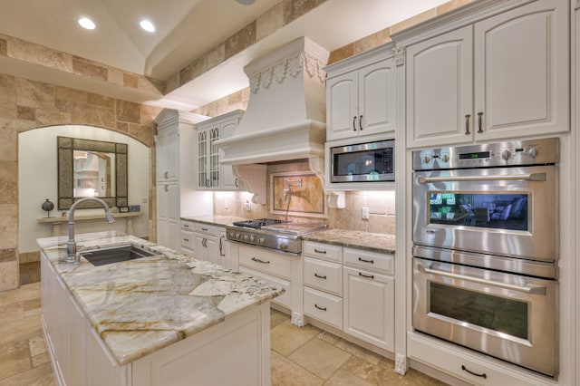 kitchen with vaulted ceiling, stainless steel appliances, custom exhaust hood, sink, and light tile floors