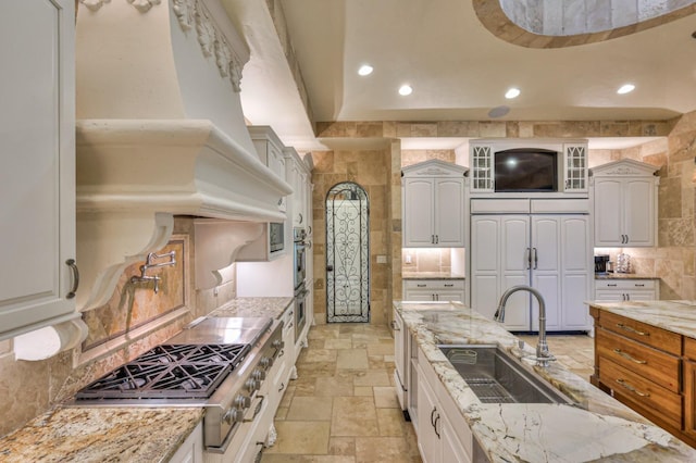 kitchen featuring stone tile floors, recessed lighting, a sink, and stainless steel gas stovetop