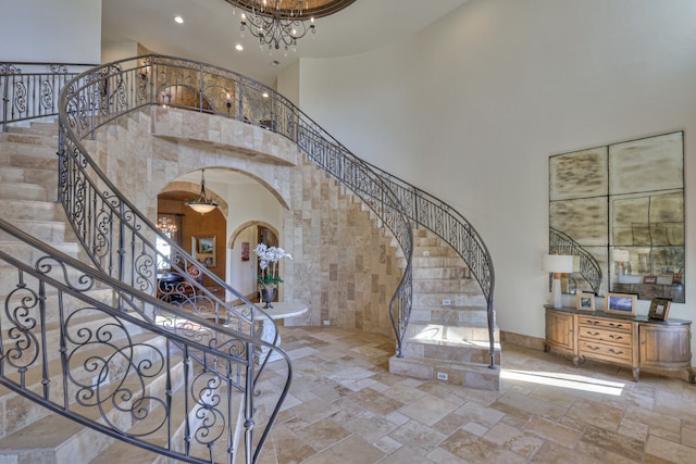 foyer with tile walls, a towering ceiling, tile flooring, and a chandelier