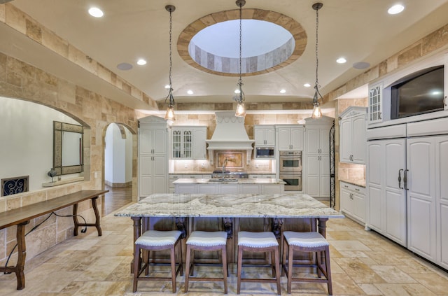 kitchen featuring appliances with stainless steel finishes, custom range hood, and a large island