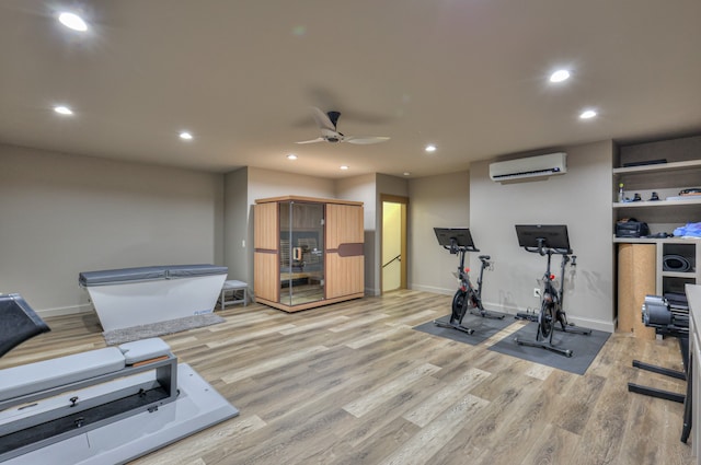 exercise area featuring ceiling fan, light hardwood / wood-style flooring, and a wall mounted air conditioner