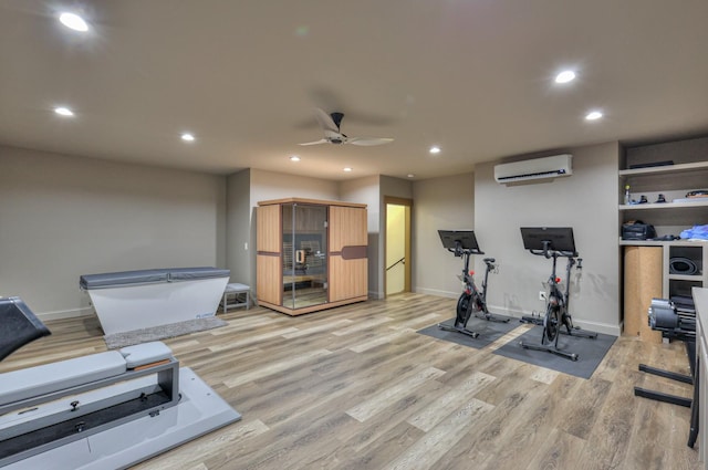 exercise room featuring light wood finished floors, recessed lighting, a wall mounted AC, ceiling fan, and baseboards