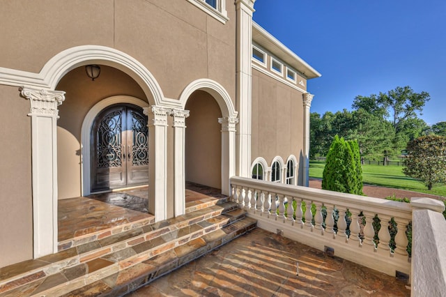 view of exterior entry with french doors, a porch, and stucco siding