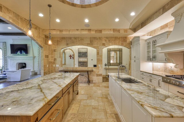 kitchen with sink, stainless steel gas stovetop, a large island, and tile walls