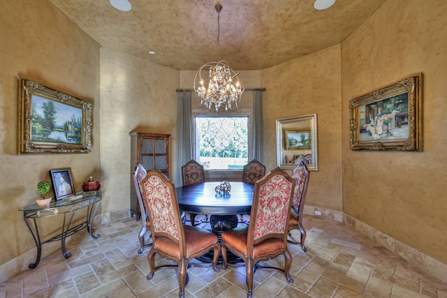 dining area with baseboards, stone tile floors, and an inviting chandelier