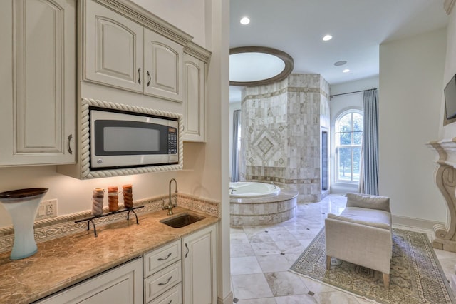 bathroom with baseboards, a sink, a bath, and recessed lighting