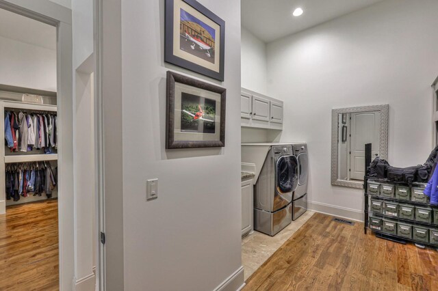 laundry room with washer and clothes dryer, cabinets, and light hardwood / wood-style floors