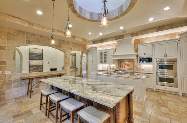 kitchen featuring stainless steel appliances, a large island, decorative light fixtures, and custom exhaust hood