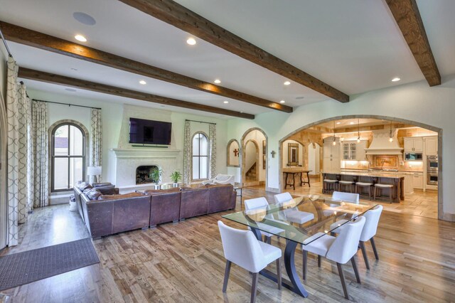 dining room featuring beamed ceiling and light hardwood / wood-style flooring