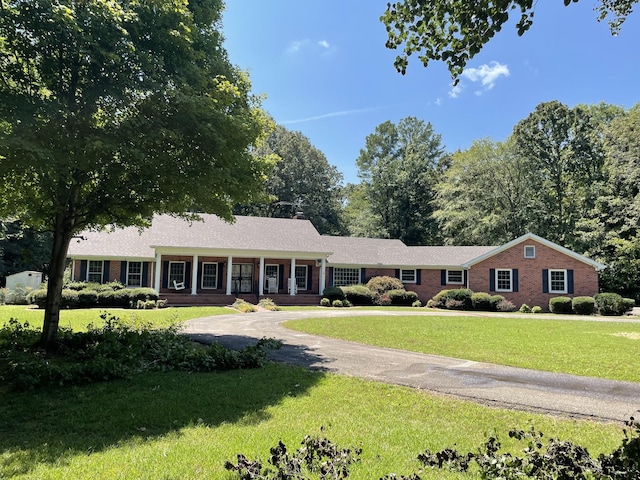 single story home featuring driveway, brick siding, and a front yard