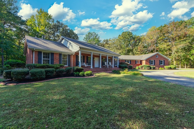 view of front of house featuring a porch, brick siding, and a front lawn