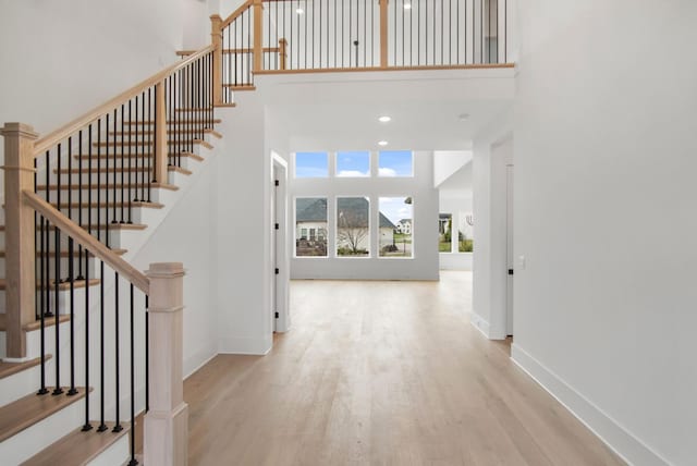 interior space featuring recessed lighting, wood finished floors, a towering ceiling, and baseboards