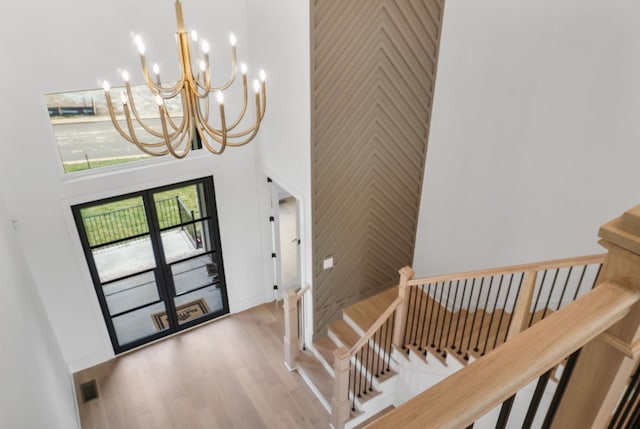 staircase with a chandelier, a high ceiling, and wood finished floors