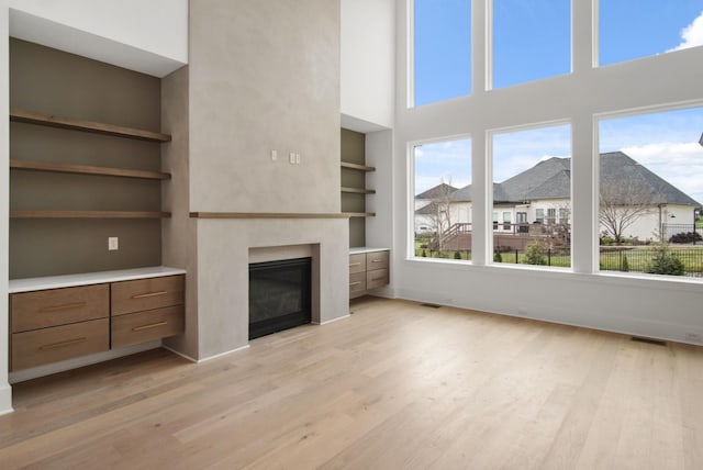 6051 Lookaway Cir, Franklin, TN 37067 - unfurnished living room with wood finished floors, a glass covered fireplace, plenty of natural light, a towering ceiling, and built in features