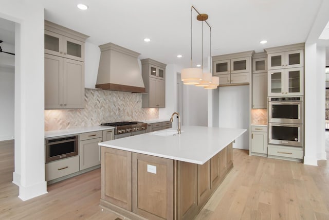 6051 Lookaway Cir, Franklin, TN 37067 - kitchen featuring stainless steel appliances, premium range hood, gray cabinetry, light wood-type flooring, and backsplash