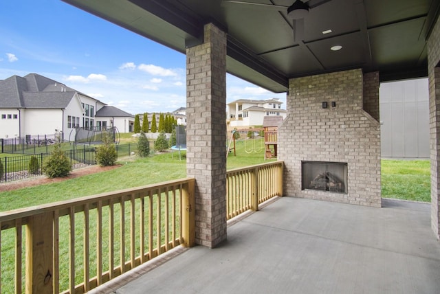 view of patio with a brick fireplace, a trampoline, a residential view, and fence