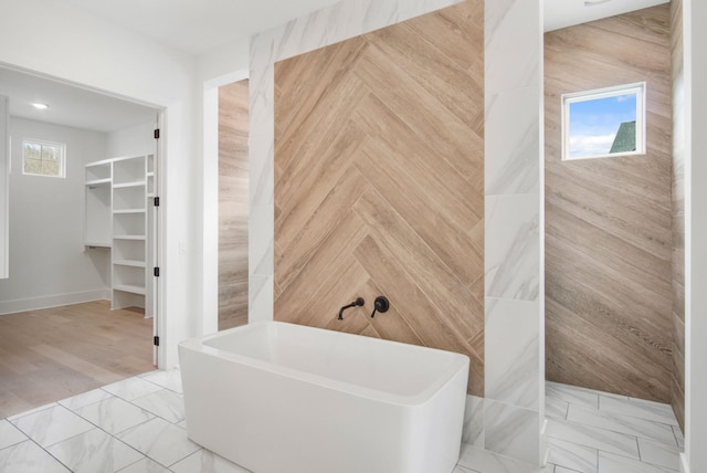 bathroom featuring a soaking tub and a walk in closet