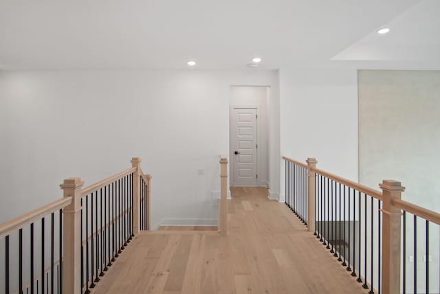 hallway with baseboards, light wood finished floors, an upstairs landing, and recessed lighting