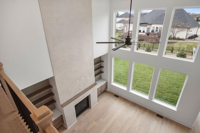 unfurnished living room featuring a tiled fireplace, light hardwood / wood-style flooring, and a high ceiling