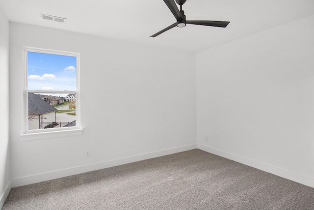 carpeted spare room with ceiling fan, visible vents, and baseboards