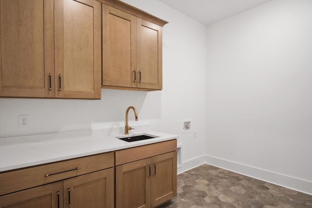 kitchen with dark floors, light countertops, a sink, and baseboards