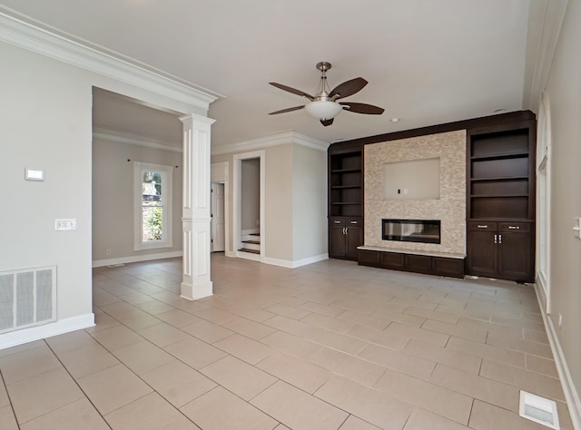unfurnished living room featuring decorative columns, ornamental molding, built in shelves, a large fireplace, and ceiling fan
