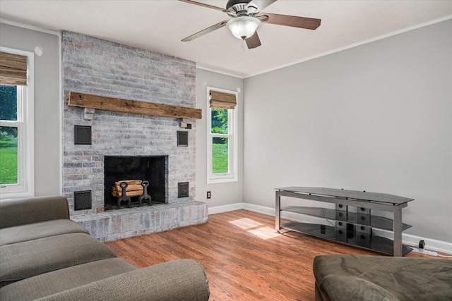 living room with brick wall, a brick fireplace, ceiling fan, hardwood / wood-style floors, and ornamental molding