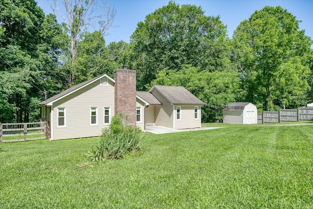 rear view of property featuring a storage unit and a lawn