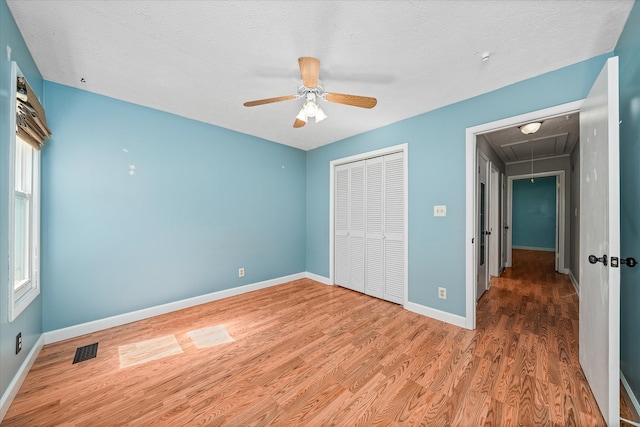 unfurnished bedroom with ceiling fan, a closet, hardwood / wood-style floors, and multiple windows