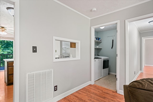 hall featuring washer and dryer, light hardwood / wood-style floors, and a textured ceiling