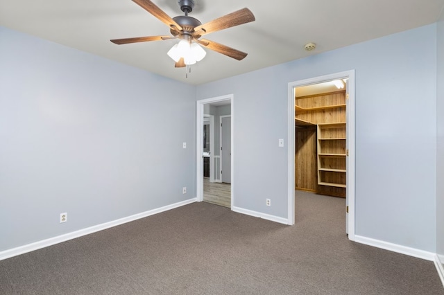 unfurnished bedroom with ceiling fan, a closet, dark colored carpet, and a spacious closet