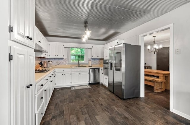 kitchen with sink, white cabinetry, decorative light fixtures, dark hardwood / wood-style floors, and stainless steel appliances