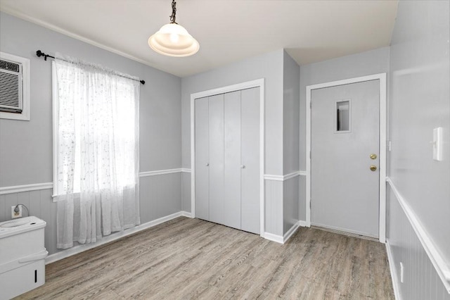 unfurnished bedroom featuring a wall mounted air conditioner, light hardwood / wood-style floors, and a closet