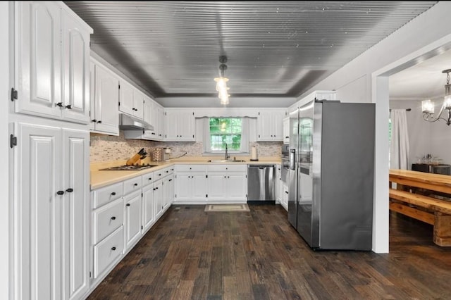 kitchen featuring appliances with stainless steel finishes, sink, white cabinets, decorative backsplash, and hanging light fixtures