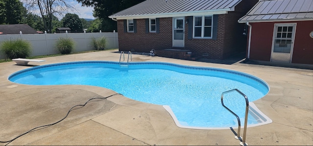 view of swimming pool featuring a diving board and a patio