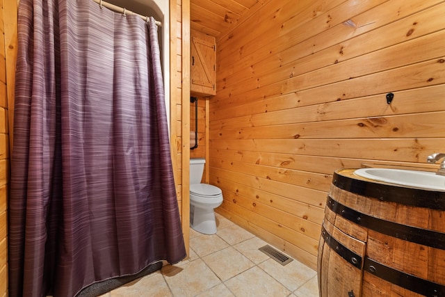 bathroom with wooden ceiling, wooden walls, toilet, and tile patterned floors