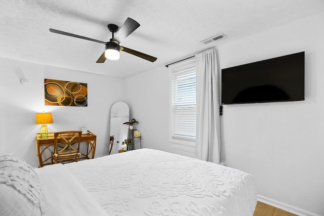 bedroom with ceiling fan, wood-type flooring, and a textured ceiling