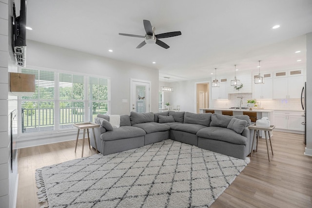 living room with ceiling fan, sink, and light hardwood / wood-style flooring