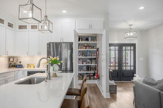 kitchen with white cabinetry, sink, decorative light fixtures, backsplash, and stainless steel fridge