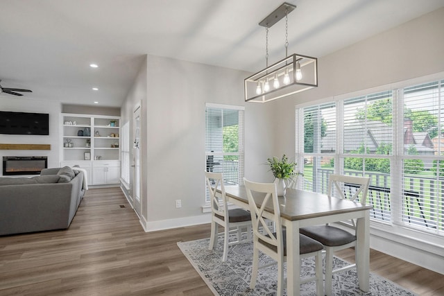 dining space with built in shelves, hardwood / wood-style floors, and ceiling fan