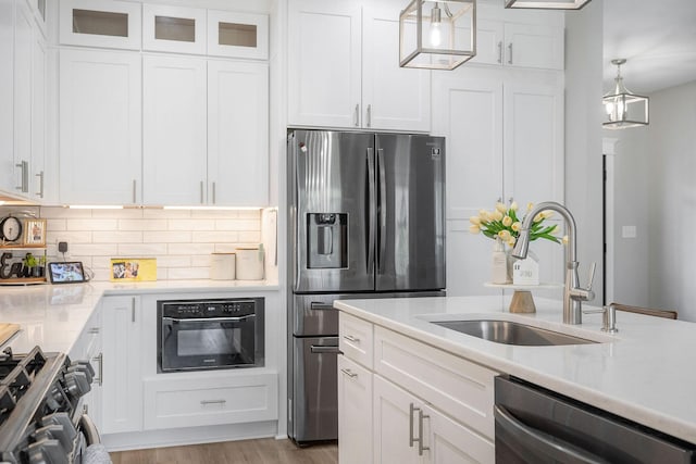 kitchen featuring black appliances, hanging light fixtures, white cabinets, sink, and backsplash