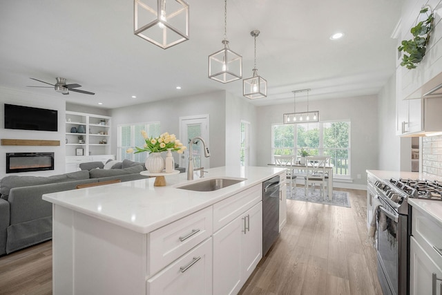 kitchen featuring white cabinets, a kitchen island with sink, appliances with stainless steel finishes, and sink