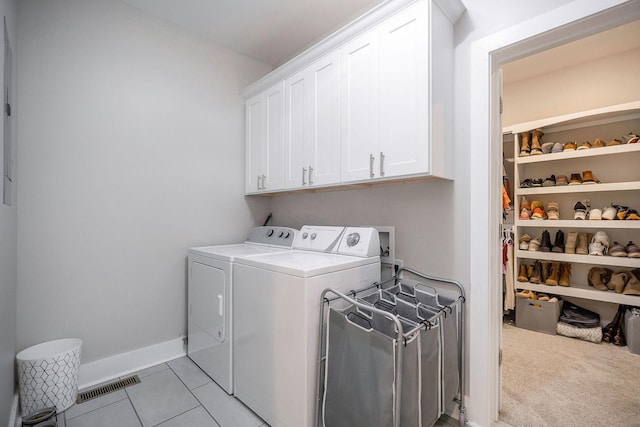 laundry room with independent washer and dryer, cabinets, and light tile patterned floors